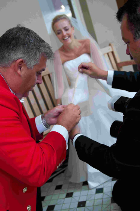 Essex Wedding Toastmaster at Down Hall sewing the hem of the Bride's dress